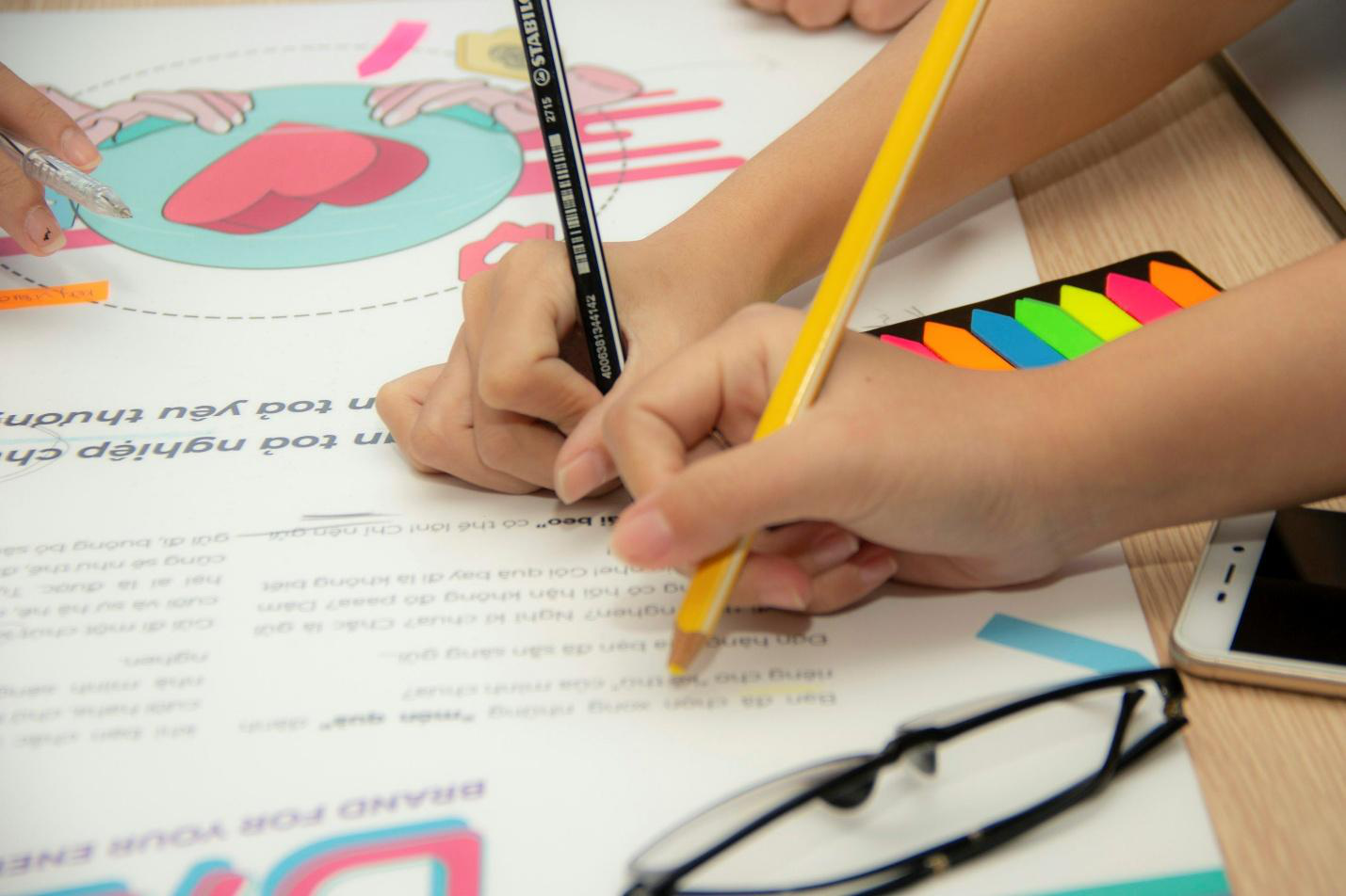 Children using pencils on a book