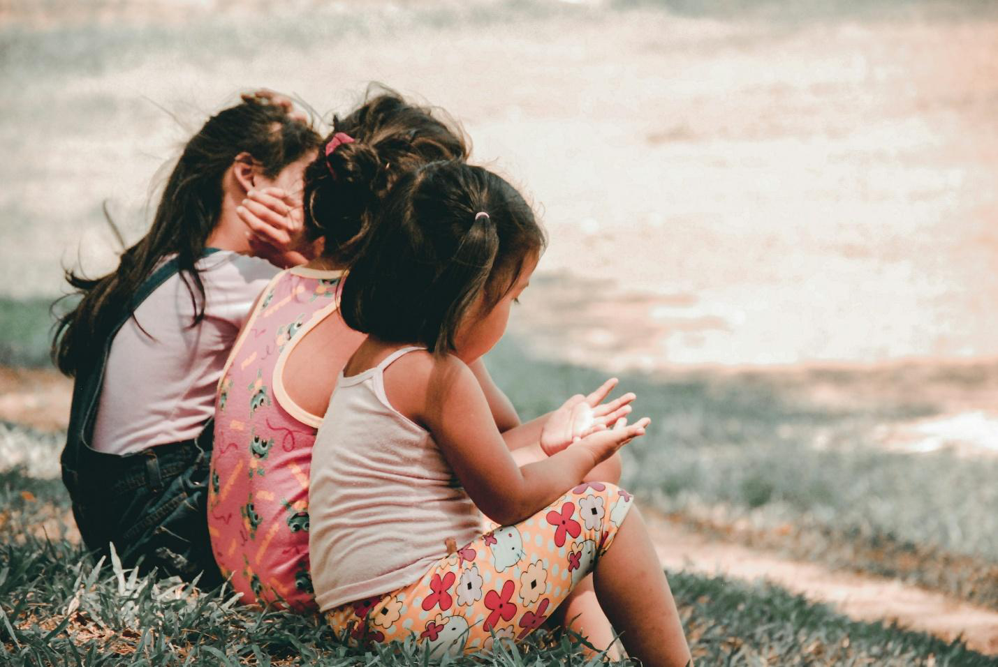 Three children sitting on the grass