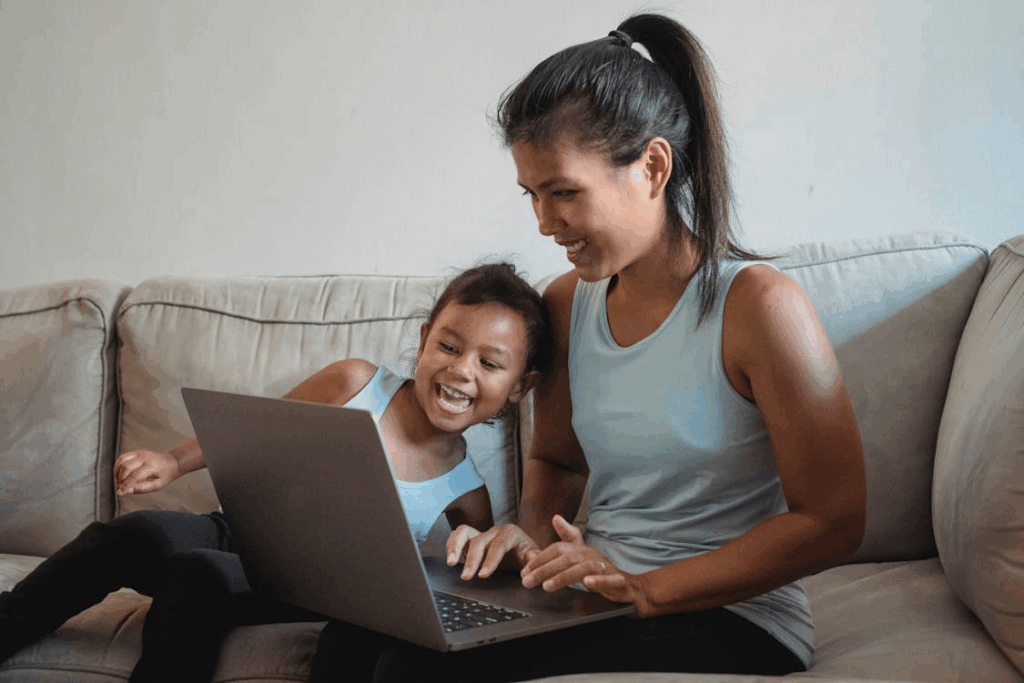 a mother and her daughter having a laugh, looking at a computer screen