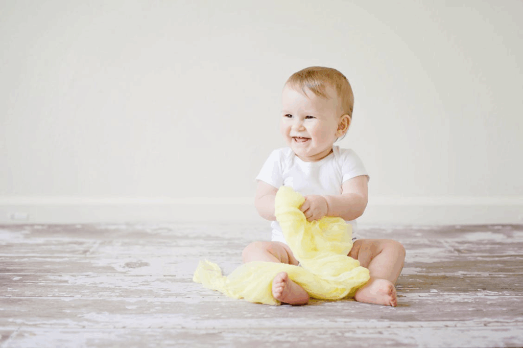 a smiling baby sitting on the floor