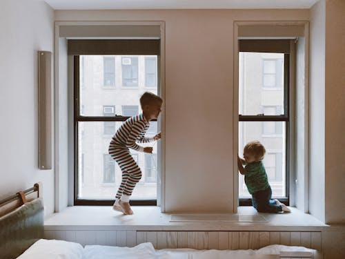 two kids playing in front of a glass window.