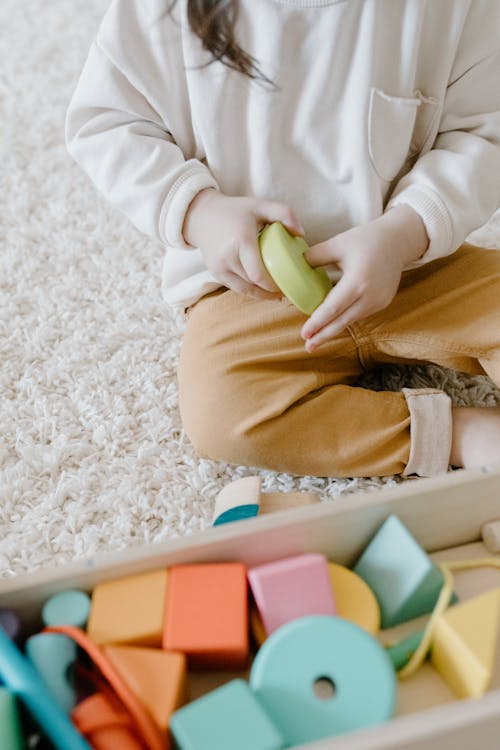 a child sitting on the floor and playing with wooden toys