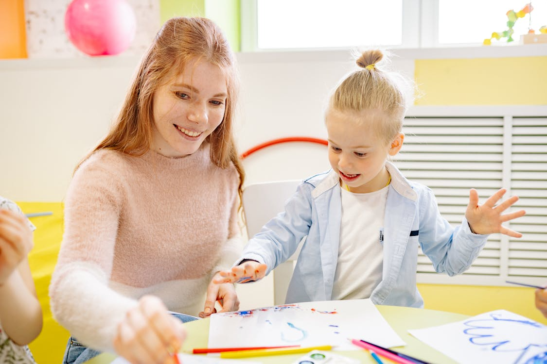 a girl learning to paint with her teacher